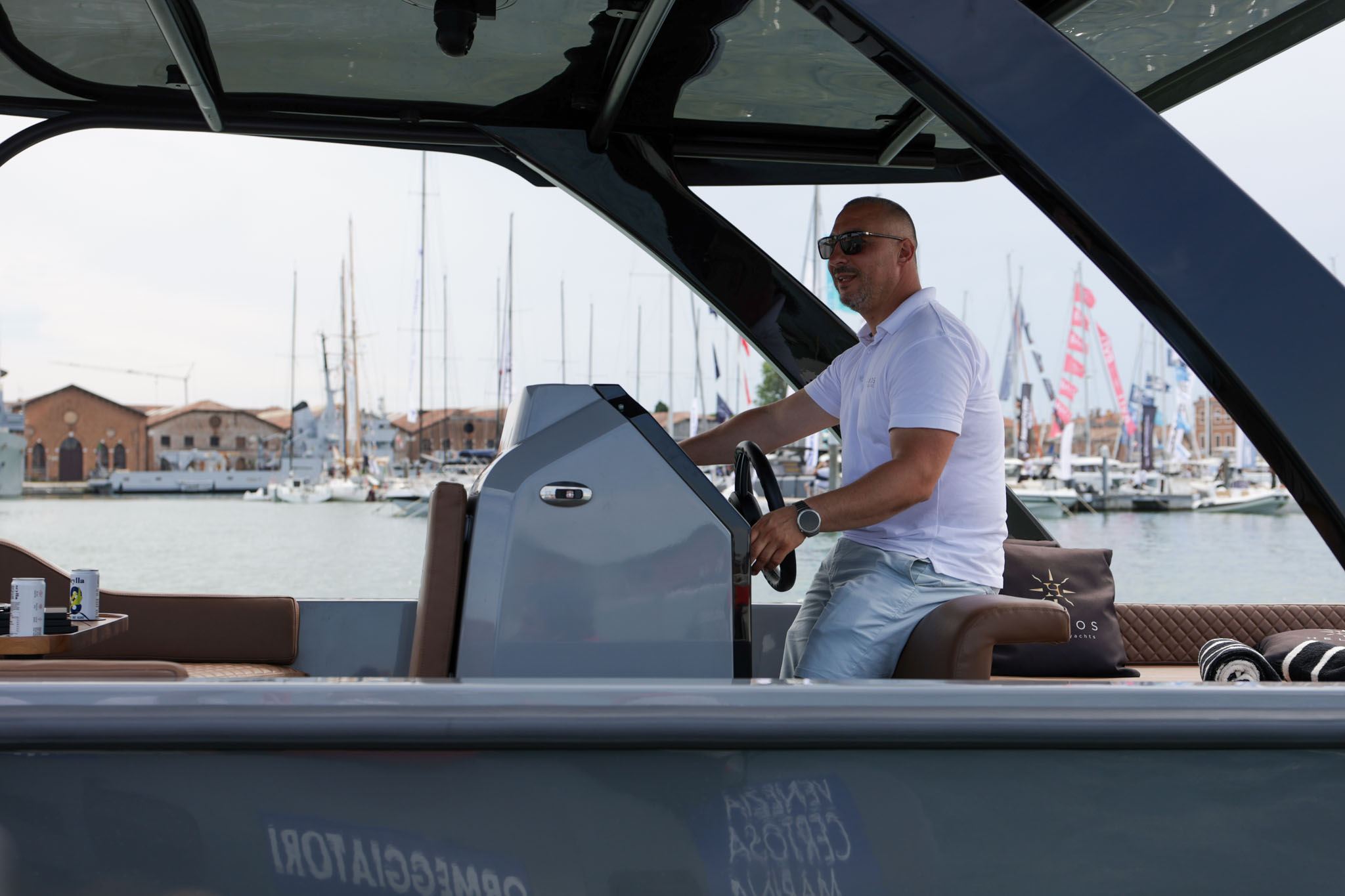 Skipper at the helm of the Helios Omega 7.2 in a marina